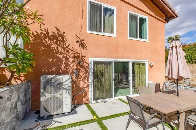 rear view of property with stucco siding, outdoor dining space, a patio area, and ac unit