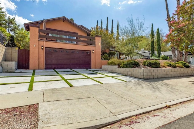 traditional home with fence, stucco siding, concrete driveway, and a balcony