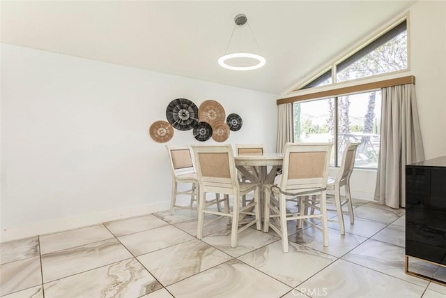 dining area featuring baseboards and lofted ceiling
