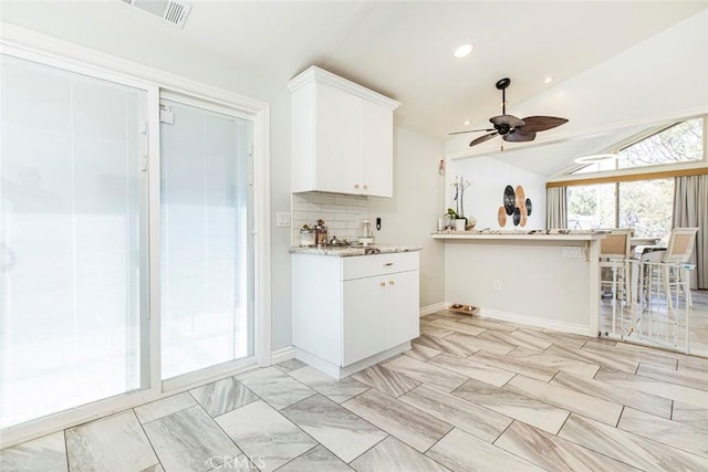 kitchen with tasteful backsplash, a ceiling fan, visible vents, white cabinets, and lofted ceiling