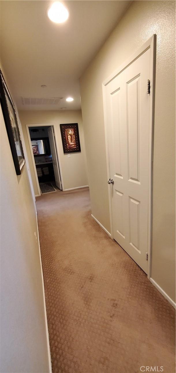 hallway featuring baseboards, recessed lighting, and carpet