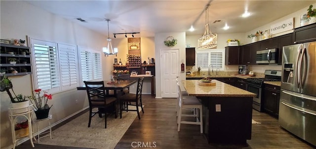 kitchen with a kitchen breakfast bar, stainless steel appliances, decorative light fixtures, and a center island