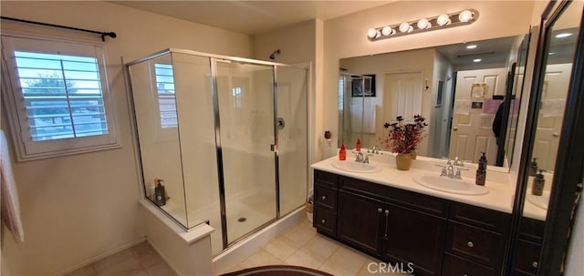 full bath featuring double vanity, a sink, a stall shower, and tile patterned flooring