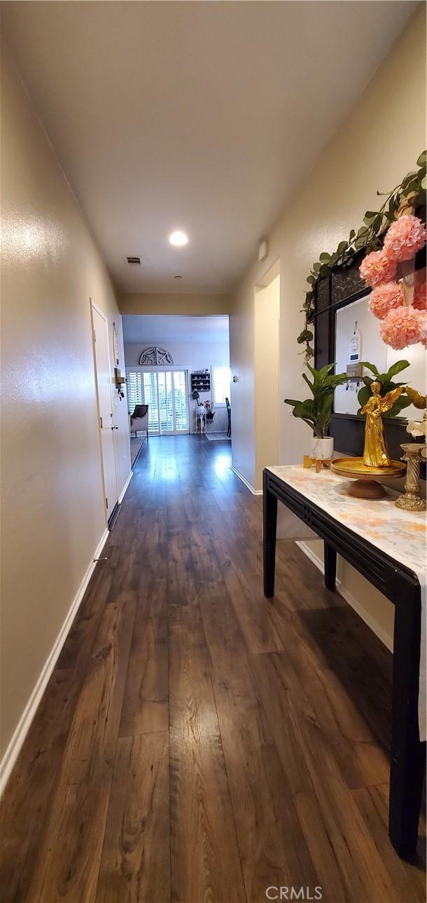 hallway with baseboards, dark wood-style floors, and visible vents