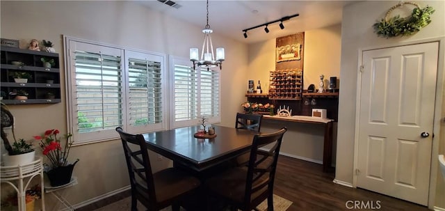 dining room with rail lighting, baseboards, a chandelier, dark wood-style floors, and visible vents
