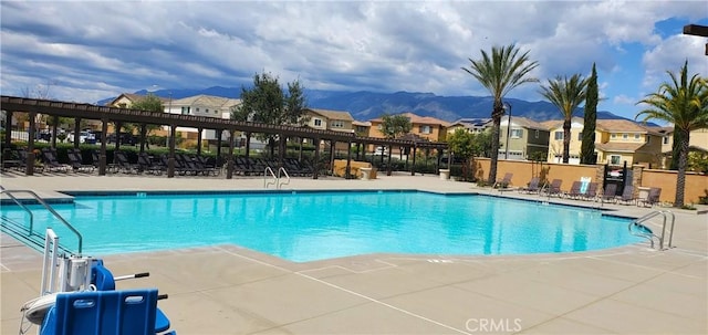 community pool featuring a mountain view, fence, and a patio