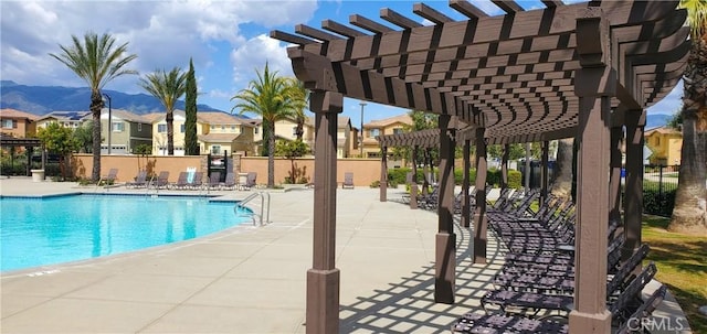community pool with fence, a patio, a residential view, a mountain view, and a pergola