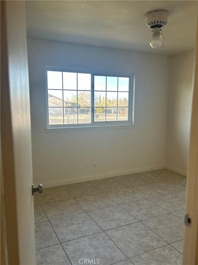 spare room featuring baseboards and light tile patterned floors