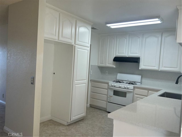 kitchen with a sink, white cabinetry, baseboards, under cabinet range hood, and gas range gas stove