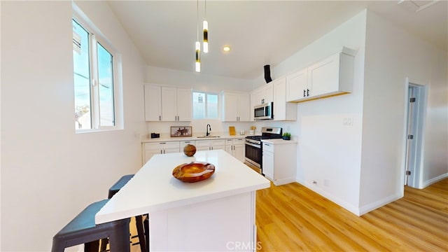 411 W Plum St, Compton, CA 90222 - kitchen featuring stainless steel appliances, a sink, light wood finished floors, a kitchen breakfast bar, and plenty of natural light