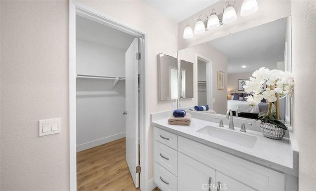 10620 Gemini Dr, Riverside, CA 92503 - bathroom featuring vanity, wood finished floors, ensuite bathroom, baseboards, and a walk in closet