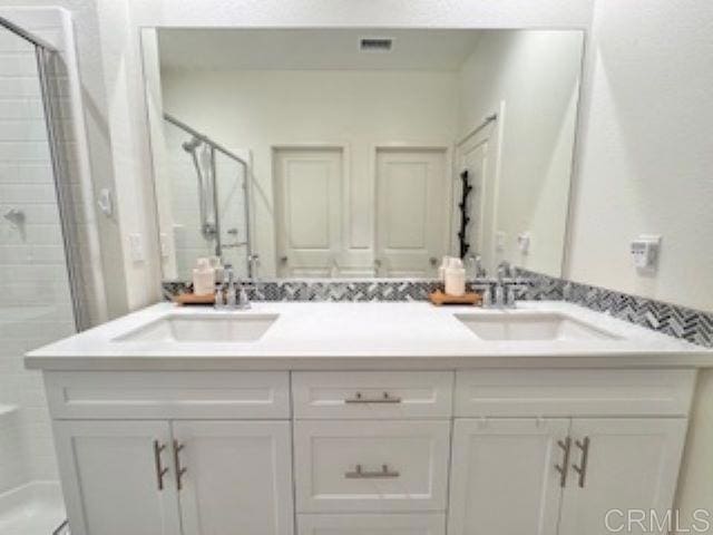 bathroom featuring a sink, a shower stall, and double vanity