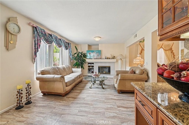 living room featuring baseboards, visible vents, and a tile fireplace