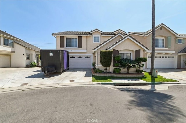 view of front of house featuring an attached garage, stucco siding, a tiled roof, and driveway
