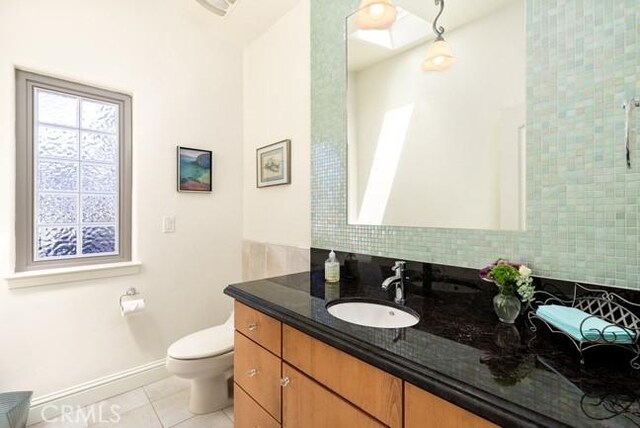 2062 Sherwood Dr, Cambria, CA 93428 - full bath with toilet, vanity, tile patterned floors, baseboards, and decorative backsplash