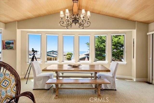 2062 Sherwood Dr, Cambria, CA 93428 - dining area featuring wood ceiling, vaulted ceiling, a chandelier, light colored carpet, and baseboards