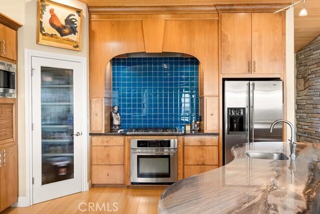 2062 Sherwood Dr, Cambria, CA 93428 - kitchen with appliances with stainless steel finishes, a sink, light wood-type flooring, and brown cabinetry