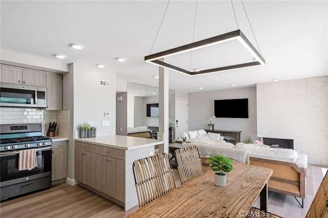 2208 The Strand, Manhattan Beach, CA 90266 - kitchen with decorative backsplash, light wood-style flooring, a peninsula, appliances with stainless steel finishes, and visible vents