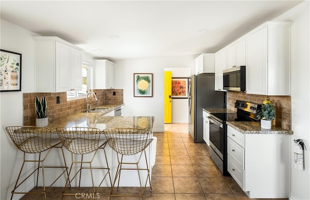 72994 Homestead Dr Unit 29, Palms, CA 92277 - kitchen featuring appliances with stainless steel finishes, a sink, a breakfast bar area, decorative backsplash, and a peninsula