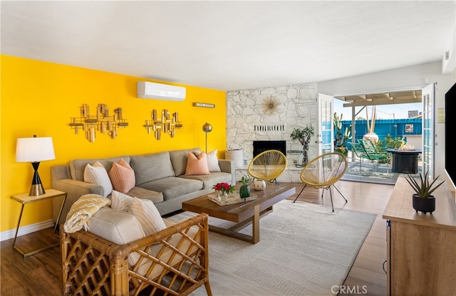 72994 Homestead Dr Unit 29, Palms, CA 92277 - living area featuring a wall mounted air conditioner, wood finished floors, a stone fireplace, and baseboards