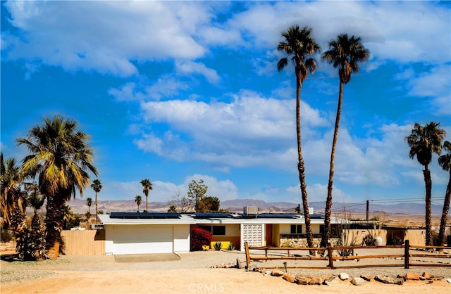 72994 Homestead Dr Unit 29, Palms, CA 92277 - view of front of home with a mountain view, dirt driveway, roof mounted solar panels, and an attached garage
