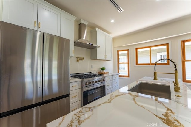 1532 W 22nd St, Los Angeles, CA 90007 - kitchen with stainless steel appliances, wall chimney range hood, white cabinetry, light stone counters, and recessed lighting