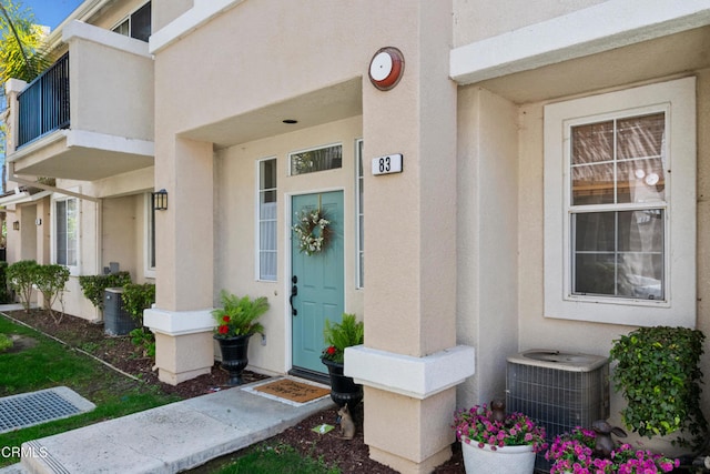 entrance to property featuring cooling unit and stucco siding