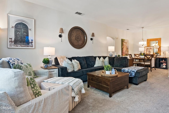 living room featuring visible vents, arched walkways, carpet flooring, and a notable chandelier