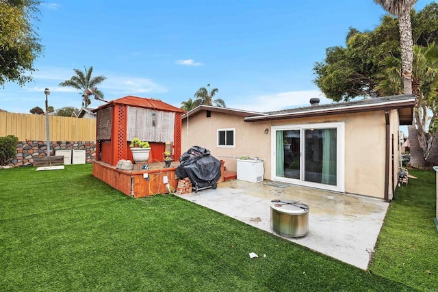 rear view of house with a patio, stucco siding, fence, and a yard