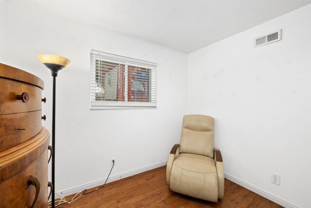 sitting room with wood finished floors, baseboards, and visible vents