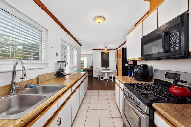 kitchen with a sink, white cabinets, light tile patterned floors, black appliances, and ornamental molding