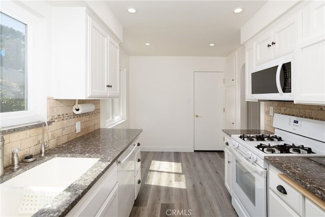 kitchen with light wood-type flooring, recessed lighting, white appliances, a sink, and white cabinets