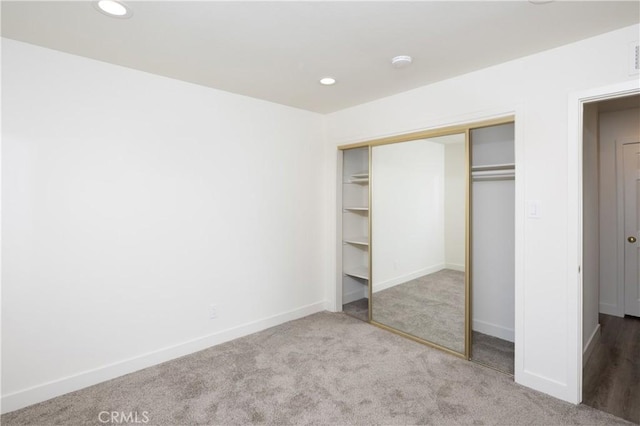 unfurnished bedroom with a closet, carpet flooring, baseboards, and recessed lighting