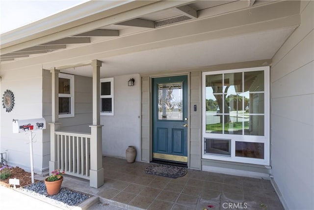 property entrance featuring covered porch and stucco siding