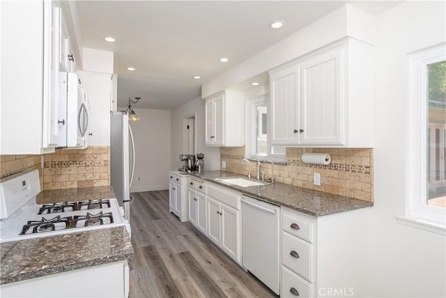 kitchen with a sink, freestanding refrigerator, dishwasher, gas range, and white cabinets