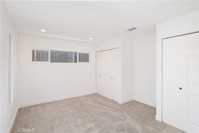 unfurnished bedroom with carpet floors, baseboards, visible vents, two closets, and recessed lighting