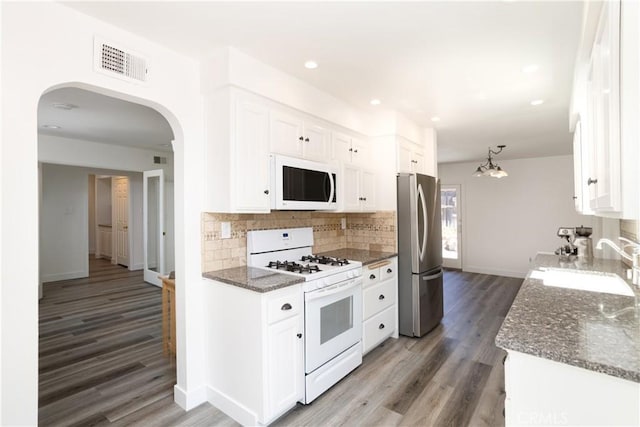 kitchen with a sink, white cabinetry, white appliances, visible vents, and arched walkways