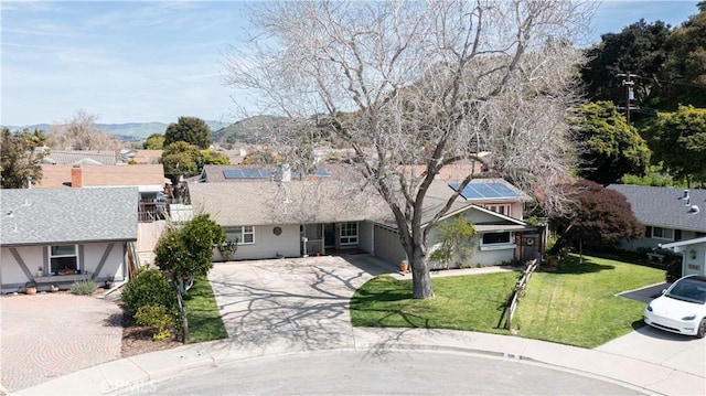 view of front of house featuring a front lawn, solar panels, a garage, and concrete driveway