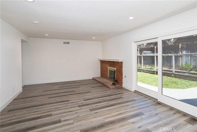 unfurnished living room with visible vents, a brick fireplace, baseboards, wood finished floors, and recessed lighting
