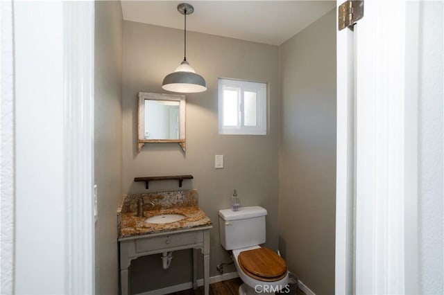 half bathroom with toilet, vanity, and baseboards