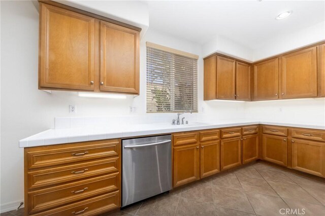 15686 Iron Spring Ln, Fontana, CA 92336 - kitchen with stainless steel dishwasher, brown cabinets, light countertops, and light tile patterned floors