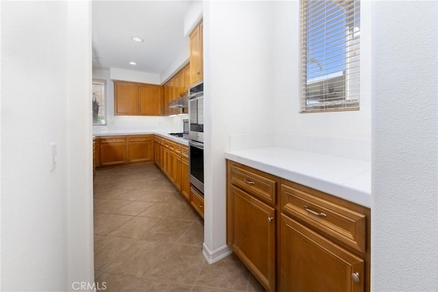 15686 Iron Spring Ln, Fontana, CA 92336 - kitchen with healthy amount of natural light, light countertops, light tile patterned flooring, under cabinet range hood, and recessed lighting