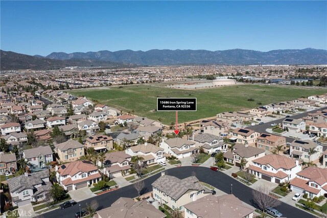 15686 Iron Spring Ln, Fontana, CA 92336 - aerial view of property and surrounding area featuring a mountainous background and nearby suburban area