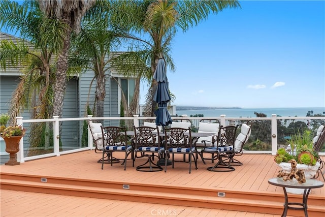 deck with a water view and outdoor dining area