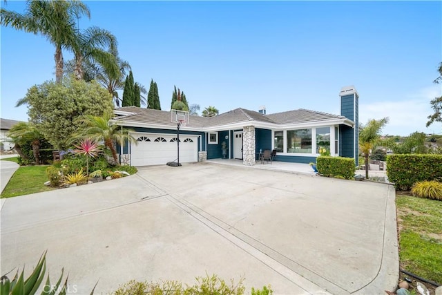 single story home with stone siding, an attached garage, a chimney, and concrete driveway