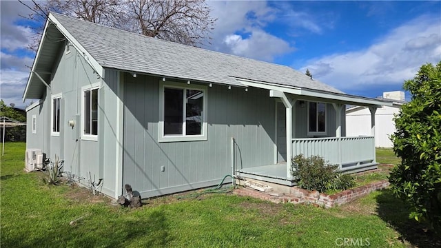 view of front of house featuring a shingled roof, a front yard, and covered porch
