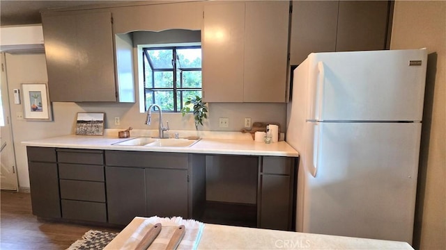 kitchen with gray cabinetry, light countertops, a sink, and freestanding refrigerator