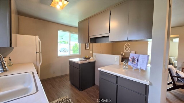 kitchen featuring dark wood finished floors, gray cabinetry, light countertops, and a sink