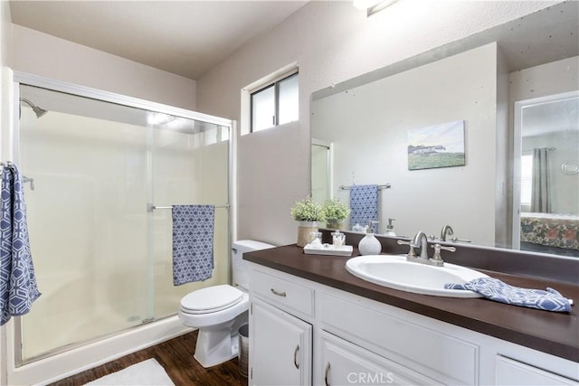 full bath featuring toilet, vanity, wood finished floors, and a stall shower