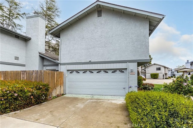 exterior space featuring stucco siding, fence, driveway, and a garage